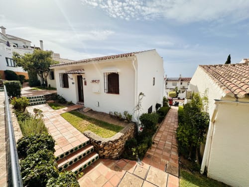 Villa blanca con tejado de barro, jardines cuidados y senderos de piedra en Nerja, España. Casita de lujo con vistas al mar