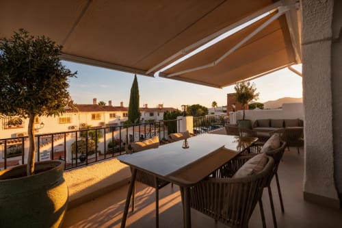 Terraza de villa de lujo al atardecer en Nerja con mesa de comedor, vistas al mar, toldo retráctil y arquitectura mediterránea