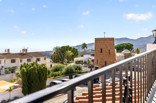 Vista de balcón de villa de lujo en Nerja con arquitectura mediterránea, palmeras y montañas al fondo