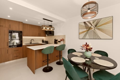 Cocina y comedor de villa de lujo moderno en Nerja con mueblería de madera, sillas verdes y vistas al mar.