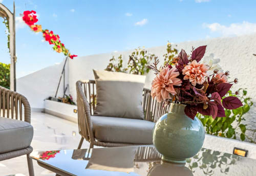 Terraza de villa de lujo en Nerja con vistas al mar, con dalias melocotón en jarrón salvia, cómodos asientos de descanso y