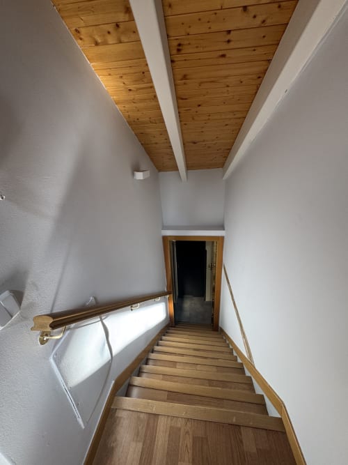 Escalera de madera con paredes blancas y vigas vistas en apartamento de Madrid con vistas a la ciudad