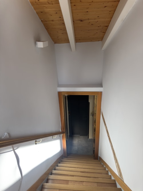 Luminosa escalera con peldaños de madera y techo de vigas en apartamento de Madrid, calle Colón