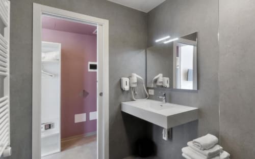 Modernes Badezimmer des Hotels Ca'Tron in Dolo mit Waschbecken, Spiegel, Handtüchern und Glasschiebetür
