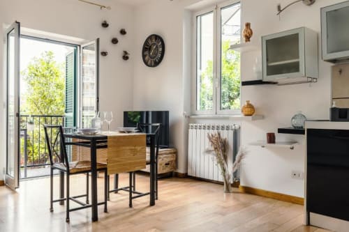 Cucina e zona pranzo moderna di Luxury Trevi House Roma, con tavolo nero, sedie in legno e vista sul balcone
