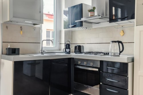 Cucina moderna della Luxury Trevi House Roma con ante nere, piani bianchi, elettrodomestici in acciaio inox e piano cottura a gas