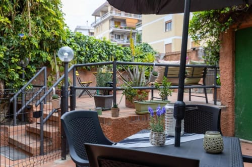 Terrazza di Trevi House a Roma con tavolo da pranzo, piante in vaso, ombrellone e vista sulla città dal patio dell'hotel di lusso
