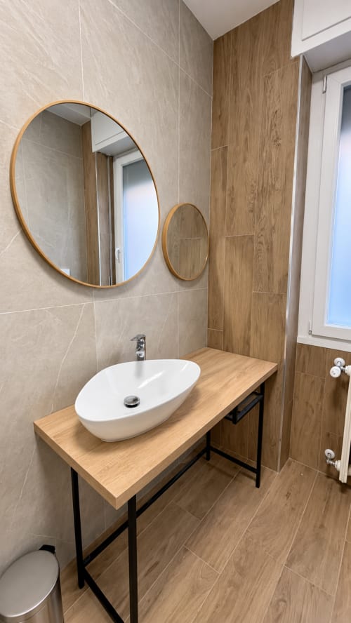 Bagno moderno a Tolstoi 13.15 con specchi ovali, lavabo bianco, mobile in legno e dettagli legno-piastrella