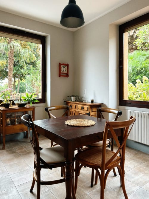 Dining room at Casa Señorial Sasueta in San Sebastián with wooden table, chairs, and garden views through large windows