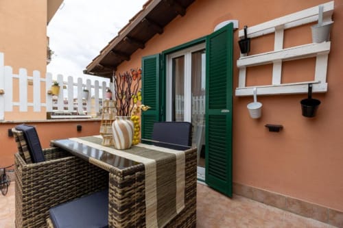 Terrazza di Trevi House con mobili in vimini, persiane verdi e piante in vaso a Roma