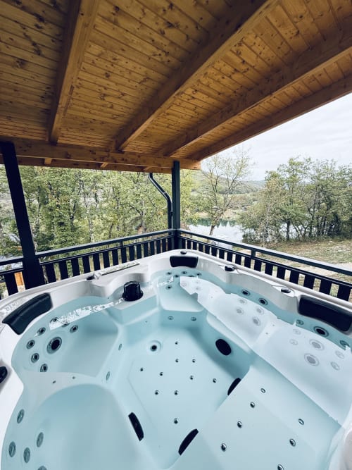 Luxuriöse Whirlpool-Badewanne auf Holzterrasse mit Blick auf die Ain und Wälder im Cabanes du Belvédère, Serrières-sur-Ain