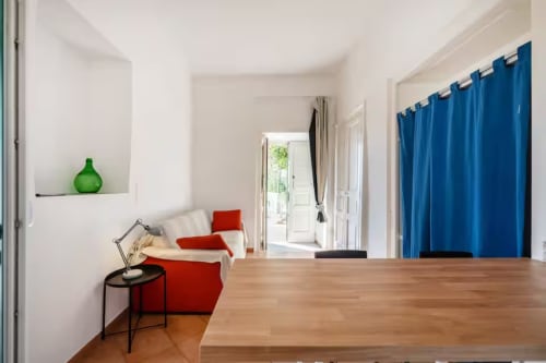Ampio appartamento presso B&B Oliveri 25 a Procida con pavimenti in legno, sedute rosse, vaso verde e tende blu