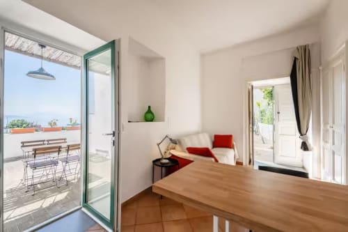 Luminoso appartamento B&B Oliveri 25 a Procida con terrazza vista mare, tavolo in legno, dettagli rossi e comfort moderni
