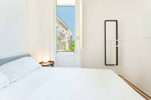 Camera luminosa di B&B Oliveri 25 a Procida con biancheria bianca, balcone con vista mare e arredamento minimalista moderno