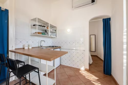 Cucina moderna nella B&B di Procida con bancone in legno, scaffali bianchi, dettagli blu e vista sul mare