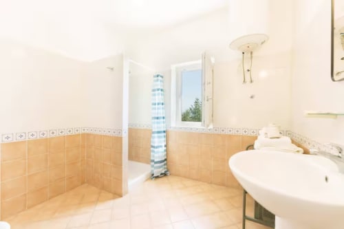 Ampio bagno di B&B Oliveri 25 a Procida con doccia, doppio lavabo e finestra con vista sul mare