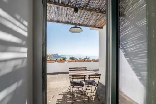 Terrazza con vista mare della B&B di Procida, zona pranzo, tenda a righe e vista costiera mediterranea