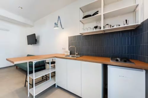 Cucina moderna nell'appartamento B&B di Procida con bancone in legno, armadi bianchi, piastrelle scure e zona pranzo