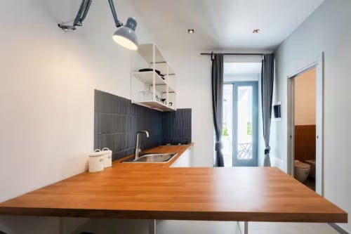 Angolo cottura moderno a B&B Oliveri 25, Procida con bancone in legno, schienale nero, lavello in acciaio inox e accesso alla vista mare