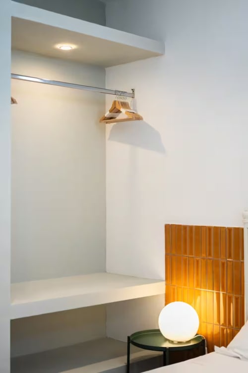 Angolo guardaroba moderno nell'appartamento di Procida con appendiabiti in legno, illuminazione incassata e arredi minimalisti