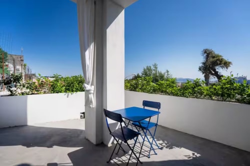 Soleggiata terrazza sul tetto di B&B Oliveri 25 a Procida con tavolo blu, sedie, vista mare e montagne
