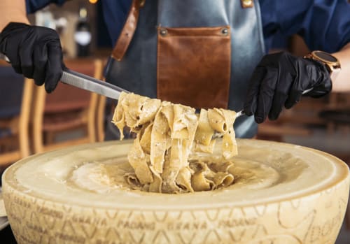 Chef del lussuoso Trevi House Roma che serve pasta fresca con precisione ed eleganza