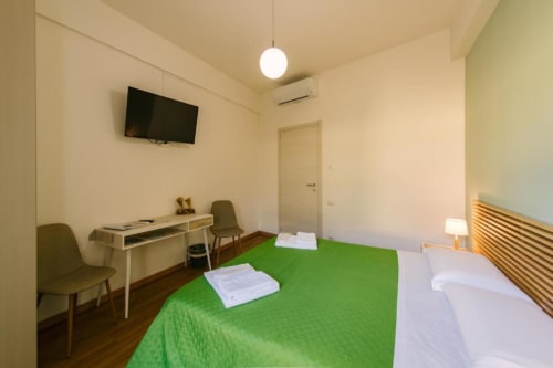 Camera Colli a Provincia di Verona: luminosa camera da letto con letto verde, scrivania, TV e testata in legno con vista interno