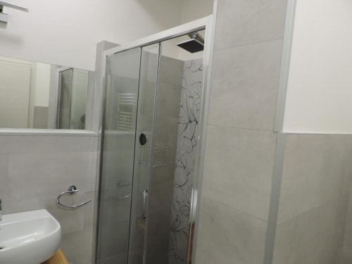 Bagno moderno nel B&B di Verona con cabina doccia in vetro, piastrelle bianche e specchio del lavabo