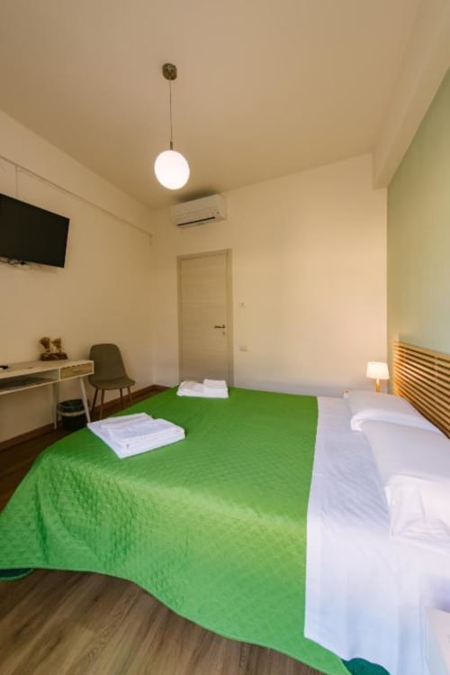 Camera moderna in B&B Provincia di Verona con letti gemelli, biancheria verde e bianca, lampada a sospensione, scrivania e interno