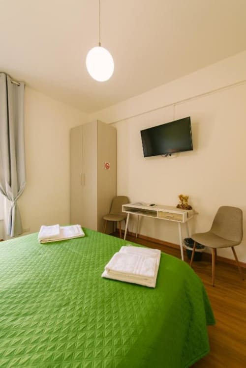 Camera luminosa a Provincia di Verona B&B con letto verde, TV, scrivania e comfort moderni a Verona, Italia
