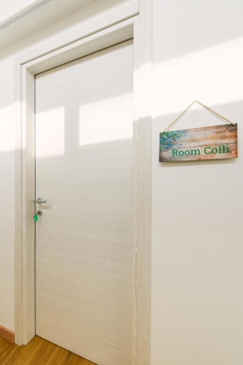 Porta in legno bianco della Camera Colli con cartello 'Room Colli' presso il B&B Provincia di Verona