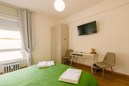 Camera luminosa del B&B a Verona con letto verde, TV, scrivania, armadio e vista sulla corte interna