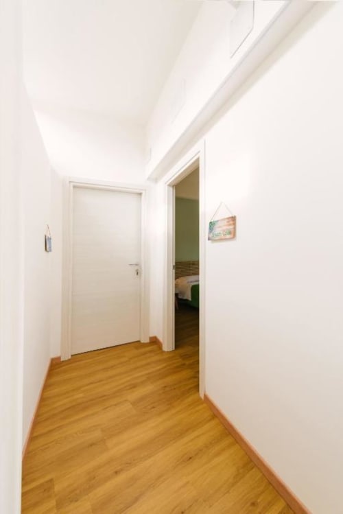 Luminoso corridoio della Camera Colli presso il B&B Provincia di Verona, con pavimenti in legno, porte bianche e arredamento moderno