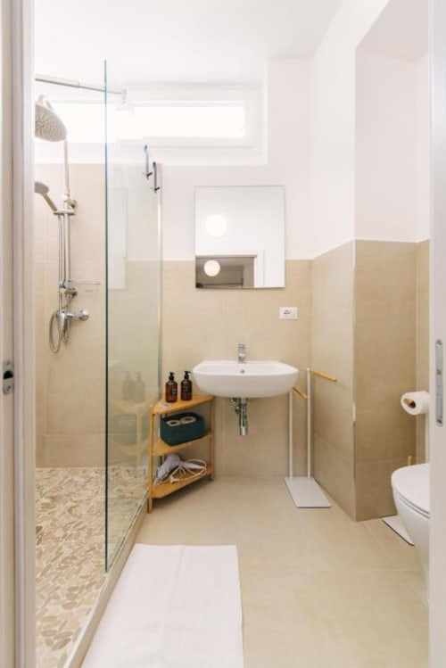 Moderno bagno nella Provincia di Verona con piastrelle beige, doccia a filo pavimento, lavabo bianco, WC e scaffalature in legno