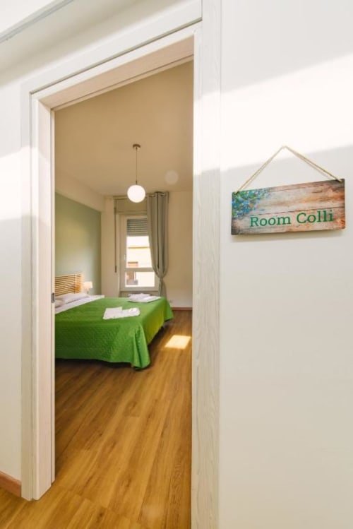 Camera Colli con coperta verde, pavimenti in legno, lampada a sospensione e vista sulla corte interna del B&B di Verona