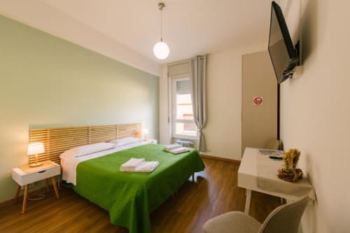 Camera moderna in B&B a Verona con copriletto verde, testata in legno, scrivania, TV e vista sulla corte interna