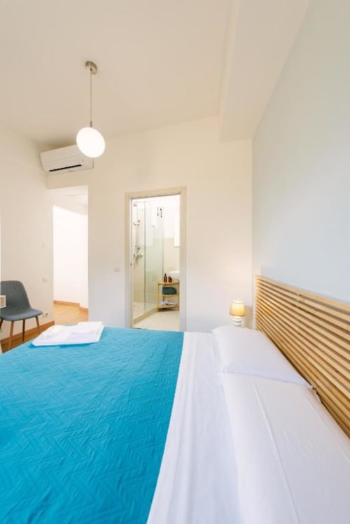 Camera da letto moderna con vista lago, biancheria turchese, testata in legno, lampada a sospensione e bagno ensuite a Provincia di