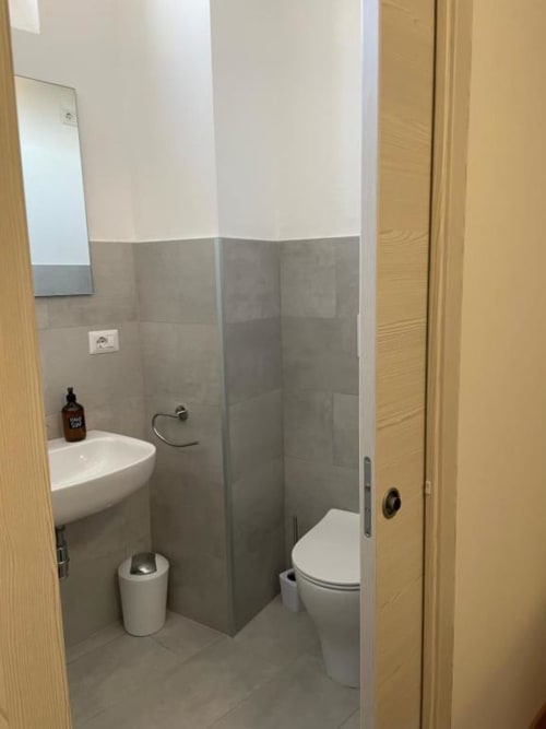 Bagno moderno presso B&B Provincia di Verona con piastrelle grigie, lavabo bianco, wc, doccia e servizi completi.