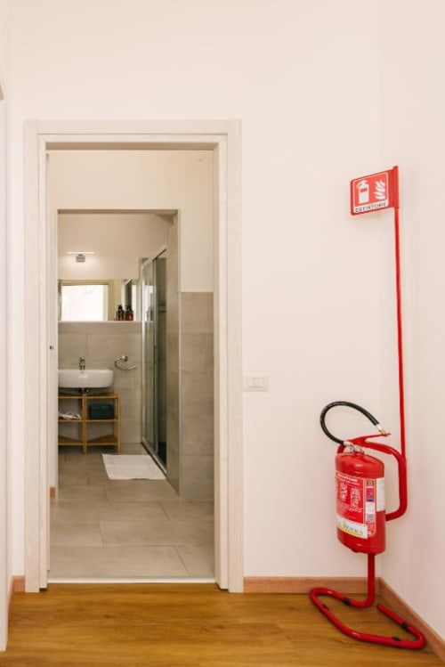 Ingresso del bagno con estintore rosso su parete bianca nella Camera Colli, Provincia di Verona B&B