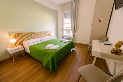 Camera moderna nella B&B di Verona con copriletto verde, testata in legno, scrivania e vista della corte interna dalla finestra