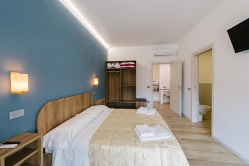 Camera Matrimoniale Moderna Peonia a Provincia di Verona B&B con parete azzurra, letto in legno, armadio e bagno ensuite