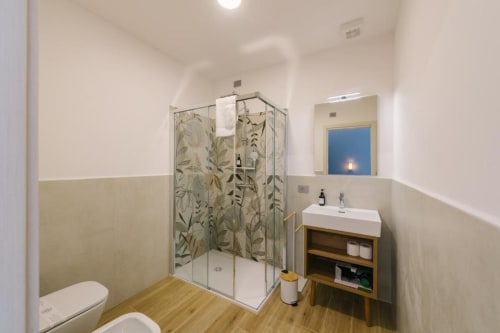 Bagno moderno presso il BnB Provincia di Verona con doccia in vetro, mobile vanità in legno, bidet e design botanico in vetro