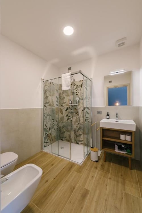 Bagno moderno della B&B di Verona con cabina doccia, mobile con lavabo in legno e pavimento effetto legno