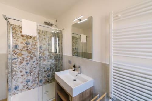 Bagno moderno della B&B di Verona con lavabo bianco, doccia con decorazioni floreali, specchio e portasciugamani