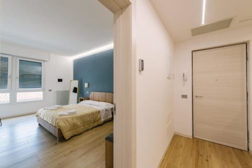 Camera matrimoniale moderna con parete blu, biancheria dorata, pavimenti in legno e arredamenti contemporanei a Provincia di Verona