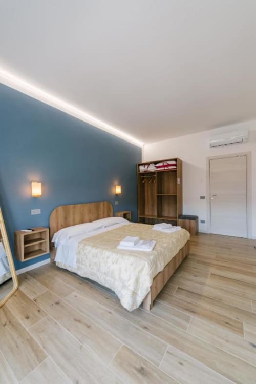 Camera da letto moderna con parete azzurra, letto in legno, pavimento in parquet e illuminazione soffusa a Verona B&B