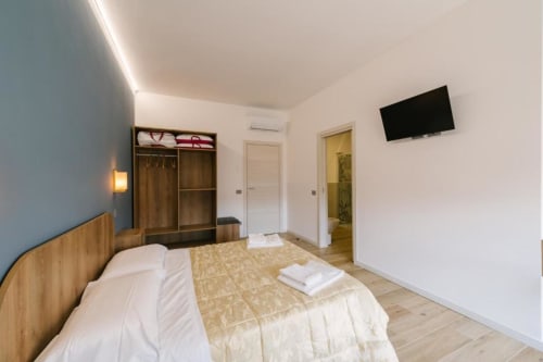 Camera doppia moderna a Verona B&B con arredamenti in legno, TV, armadio e porta del bagno en-suite