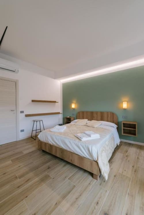 Camera moderna a Camera Olivo in Provincia di Verona con parete salvia, letto in legno, illuminazione soffusa e pavimento in parquet