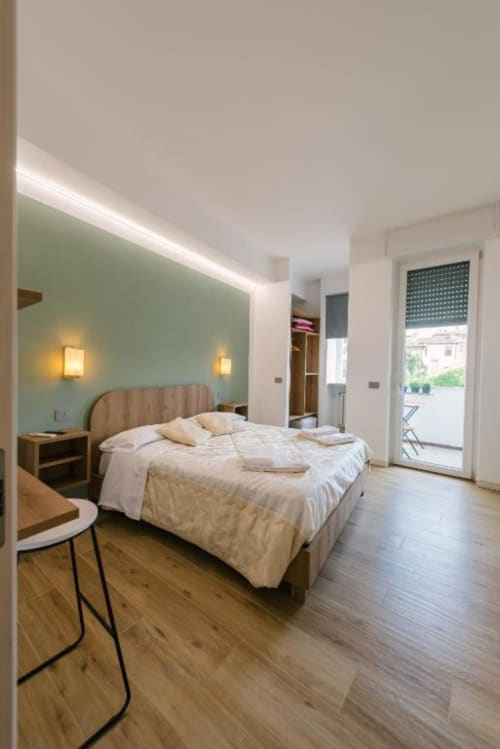 Camera moderna della B&B di Verona con parete accent verde menta, letto in legno, accesso alla terrazza e vista sui monumenti
