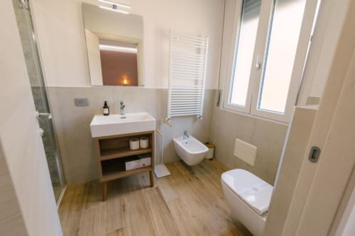 Bagno moderno in B&B a Verona con vanità in legno, doppi wc, scaldasalviette e vista sulla città dalle finestre